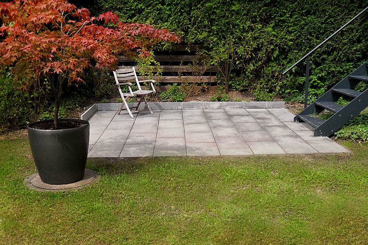 �bergang von einer Treppe in den Garten: Nachher-Situation mit gepflasterter Sitzecke